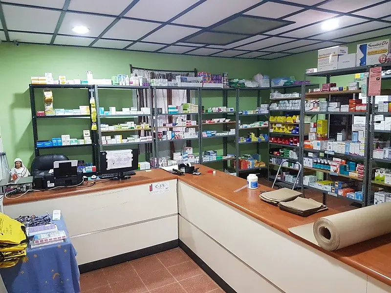 Gefüllte Medikamentenregale hinter dem Tresen der Apotheke